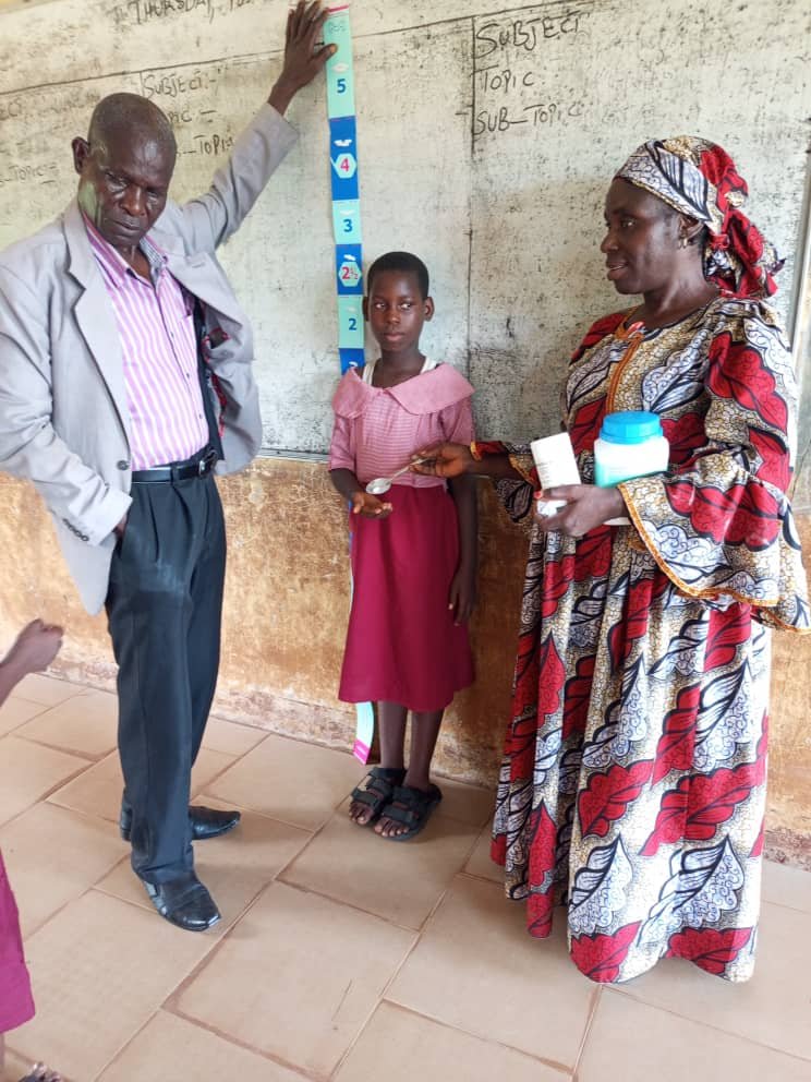 teacher fiving abendazole to kids
